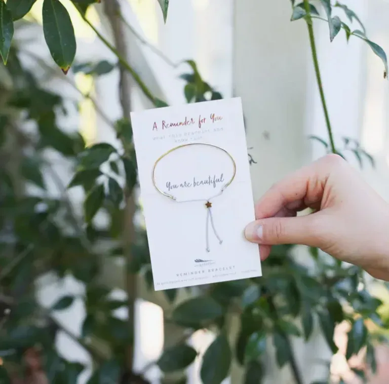 Hand holding a card with a bracelet; text reads 