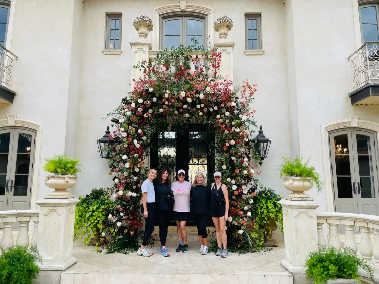 Group of people posing in front of a house with floral arch.