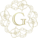 Gold letter "G" encircled by a floral and ribbon wreath.