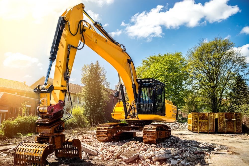 Yellow excavator on rubble, sunny day with blue sky and trees. — Des’s Driving School in Callala Bay, NSW