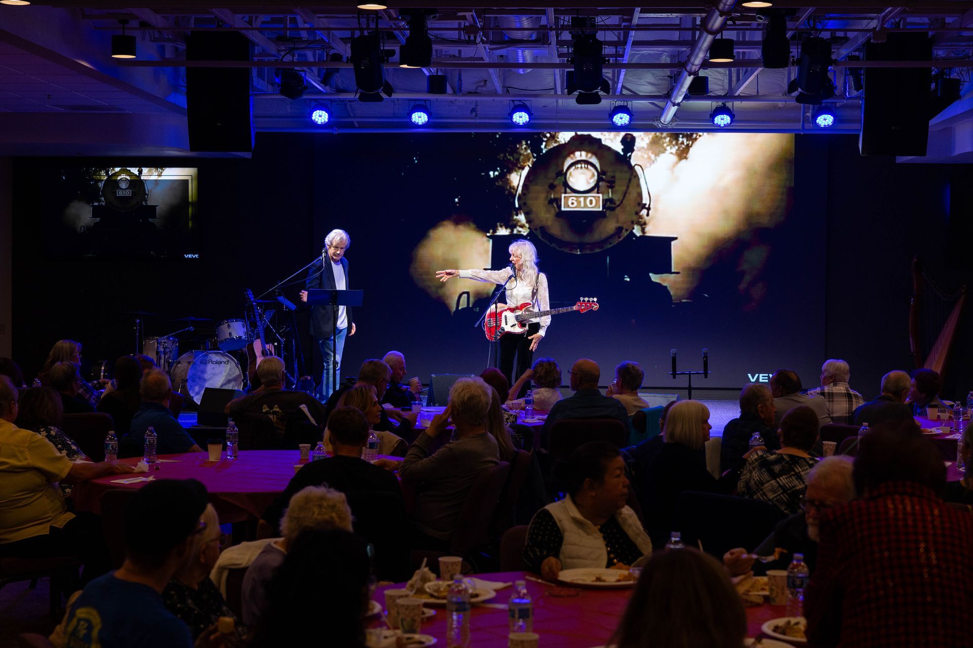 Live band performing on a dimly lit stage with blue lights in front of an audience.