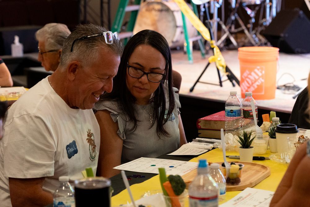 People seated at a table reviewing papers at a casual indoor event.