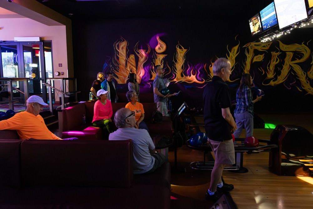 People dancing in a dimly lit nightclub with neon lights and a DJ booth