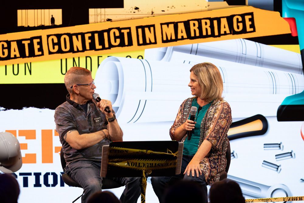 Two speakers on stage in front of a banner reading “GATE CONFLICT IN MARRIAGE”