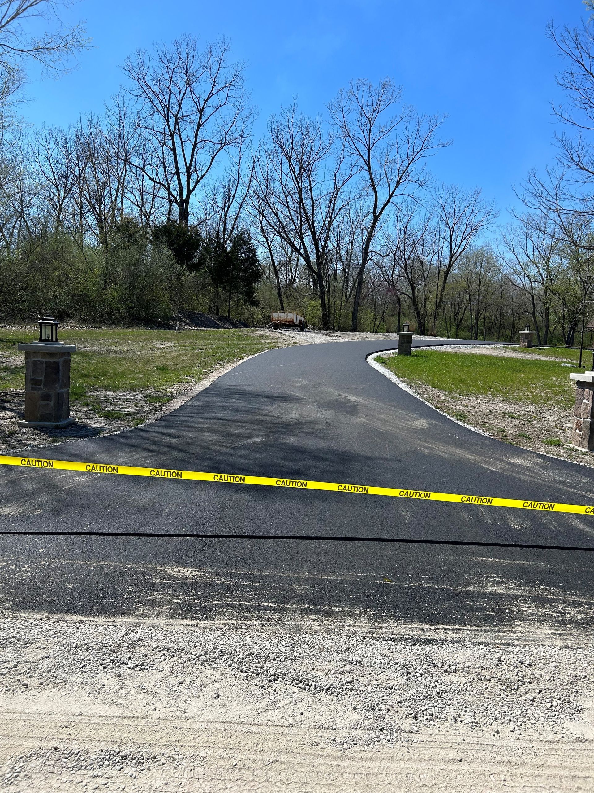 A road with a yellow tape on it and trees in the background