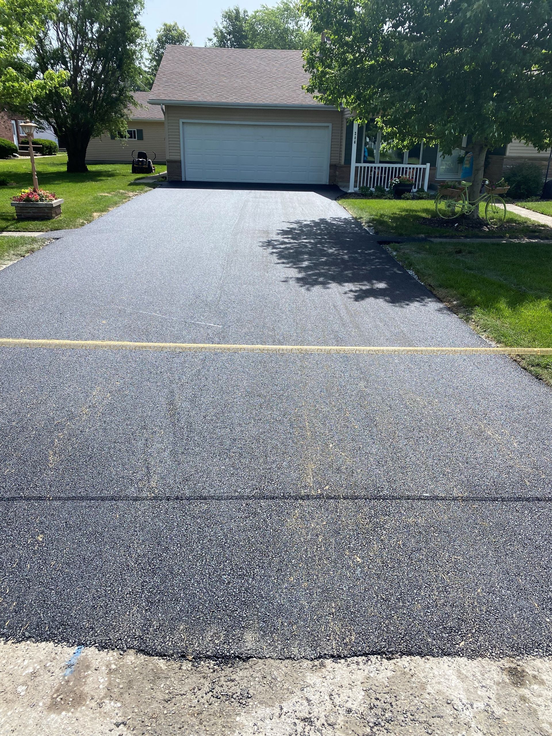 A driveway with a garage in the background and a house in the background.