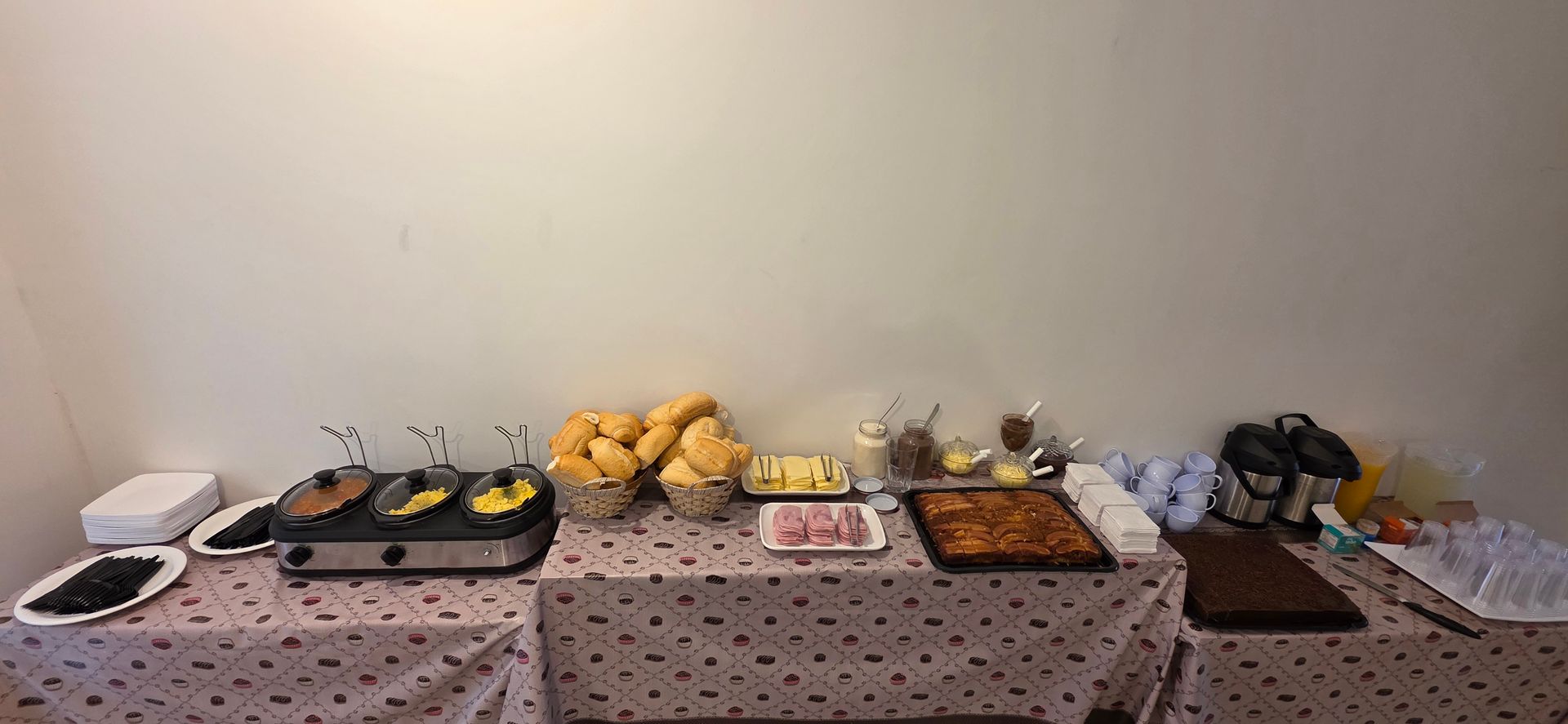 Um buffet de café da manhã com diversos itens, incluindo doces, manteiga, presunto e uma chapa.