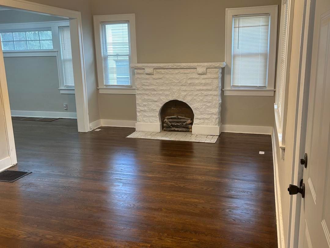 An empty living room with a fireplace and hardwood floors.