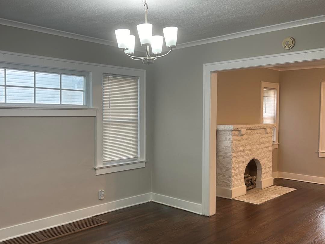 An empty living room with a fireplace and a chandelier.