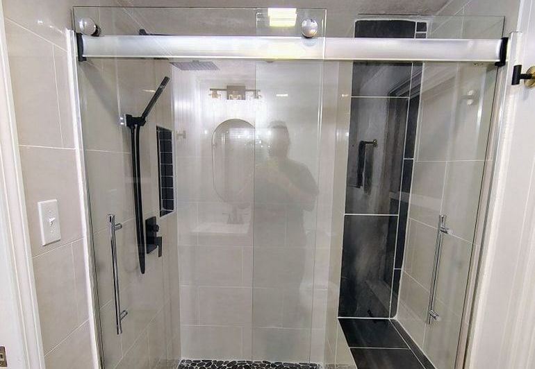 A bathroom with a sliding glass shower door and a bench.