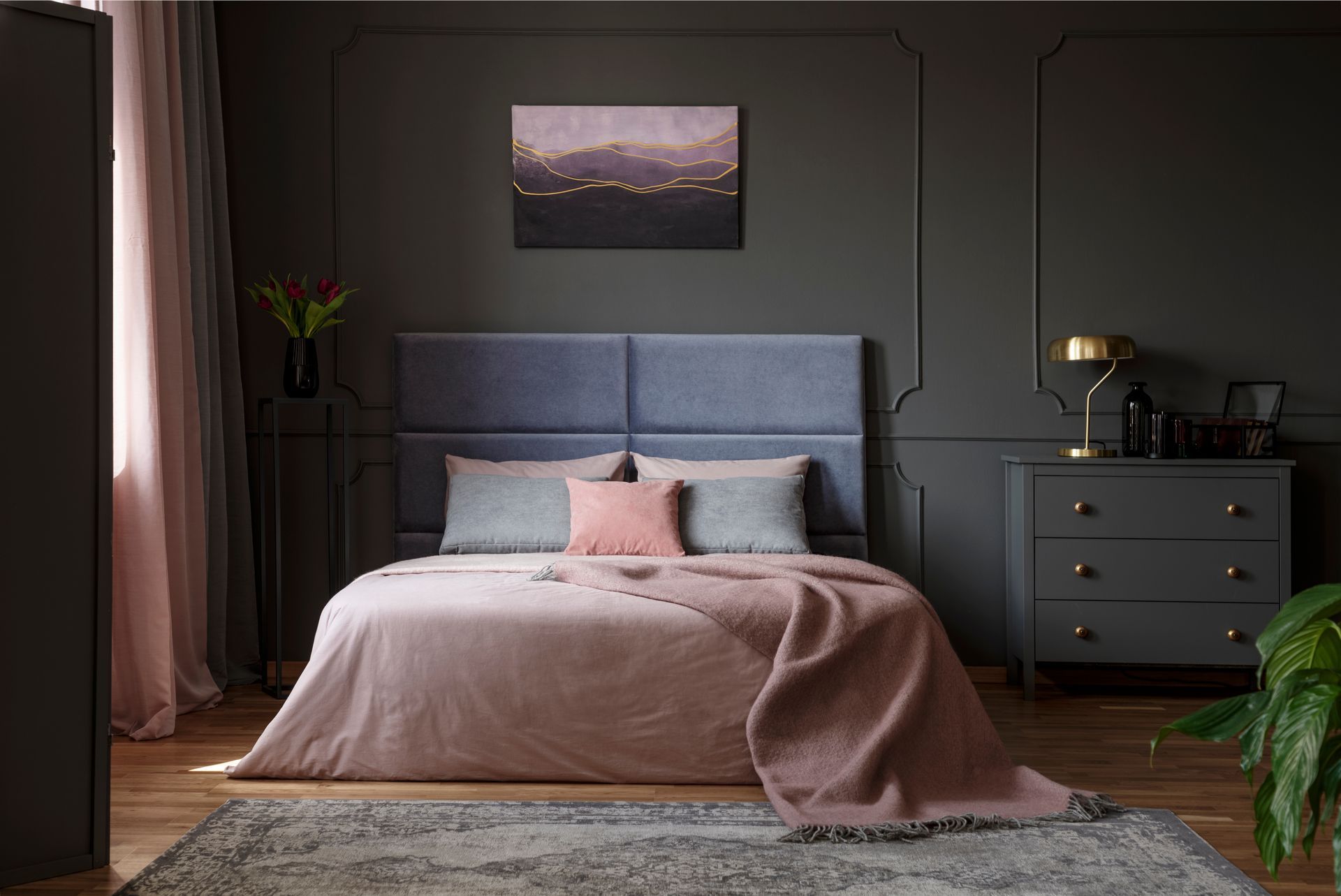 A bedroom with a bed , dresser , rug and painting on the wall.