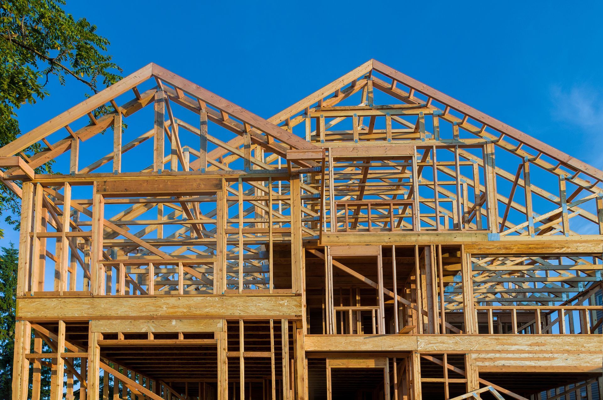 A large wooden house is being built with a blue sky in the background.