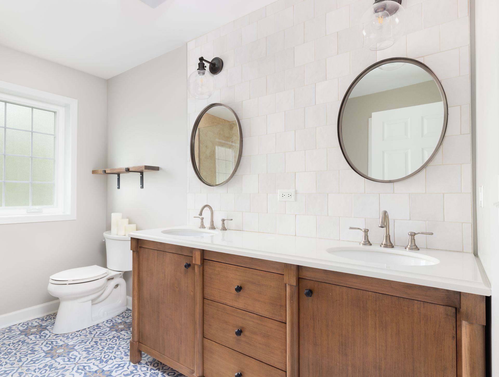 A bathroom with two sinks , two mirrors and a toilet.