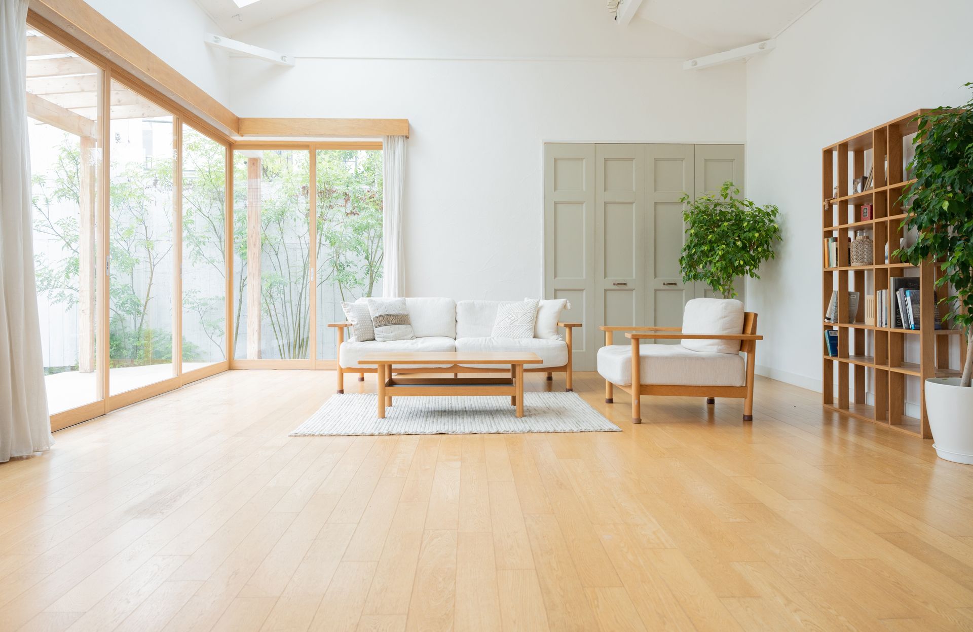 A living room with a couch , chair , coffee table and lots of windows.