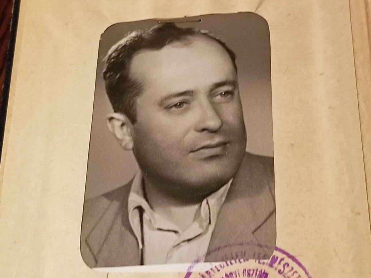 Black-and-white portrait of a man in a suit jacket and open-collared shirt, looking slightly to the side.