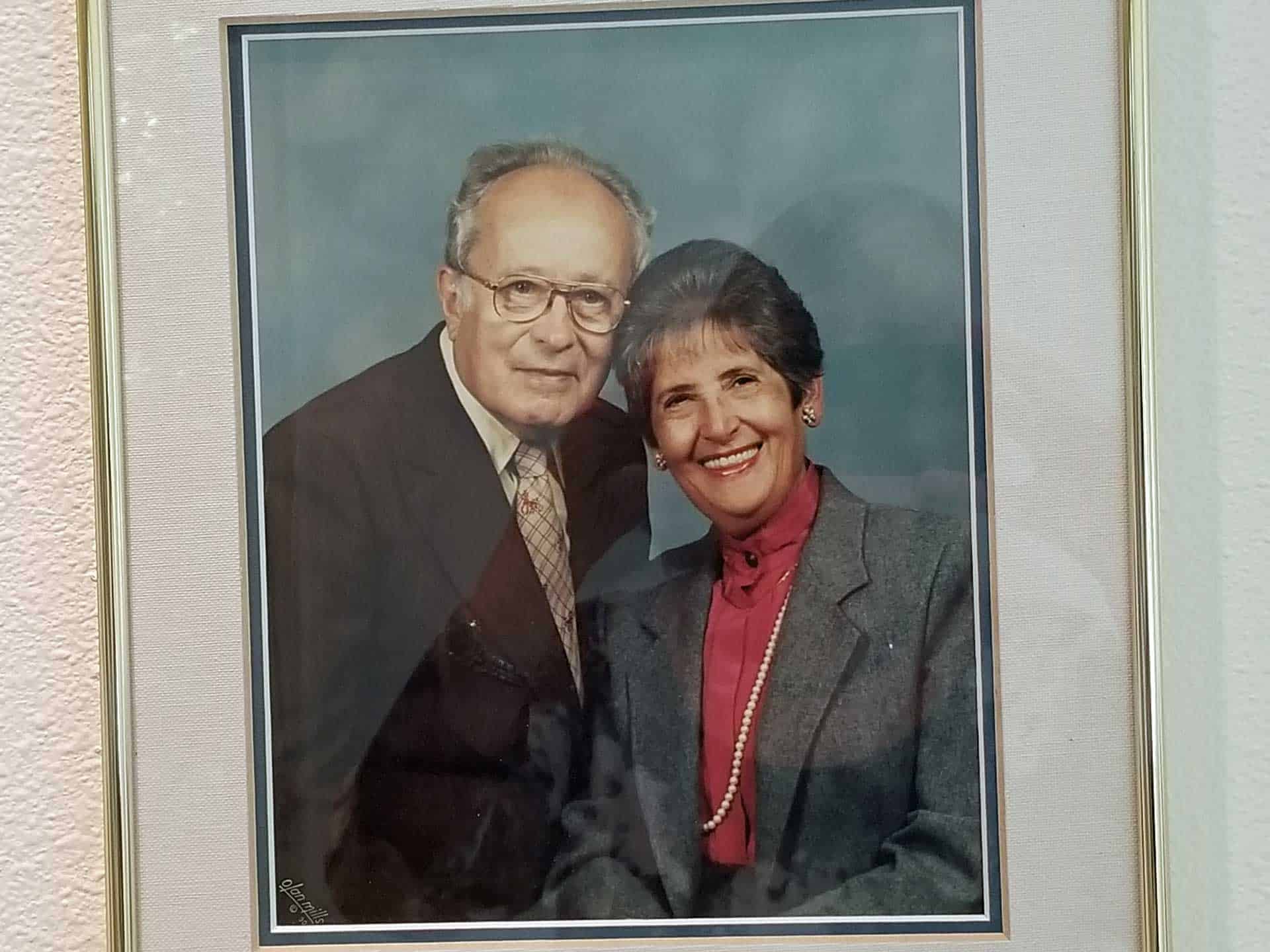 Framed portrait of a smiling couple in formal attire against a light background