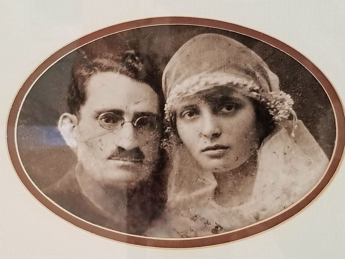 Sepia oval portrait of two solemn people, one with glasses and mustache, one in a veil and headpiece.