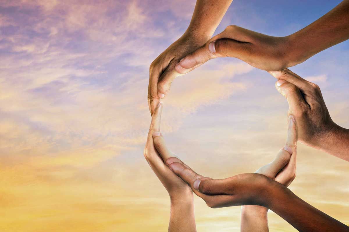 Hands forming a circle against a sunset sky with clouds