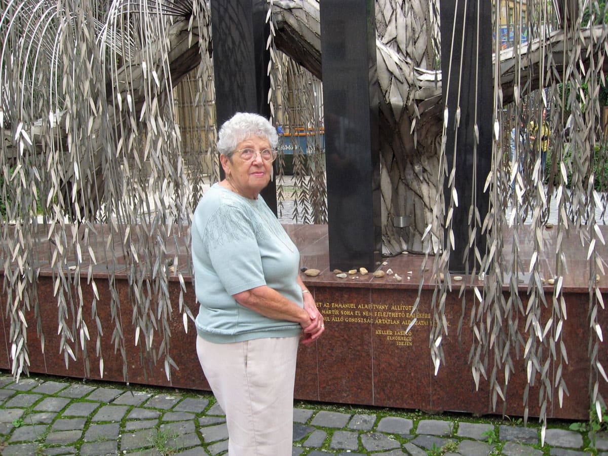 Woman standing in front of a fountain with hanging water streams and brick wall backdrop