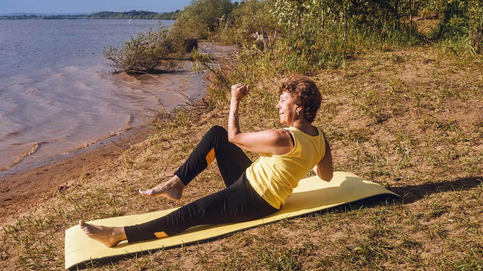 senior-woman-making-yoga-and-pilates-near-river-in