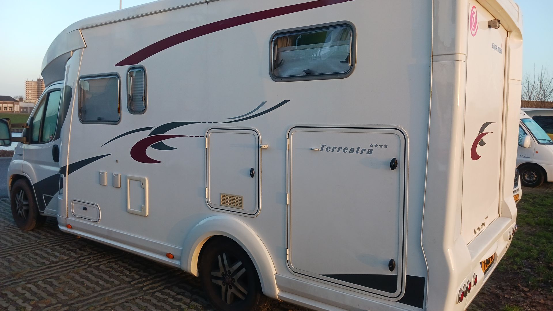Een witte camper staat geparkeerd op een parkeerplaats.