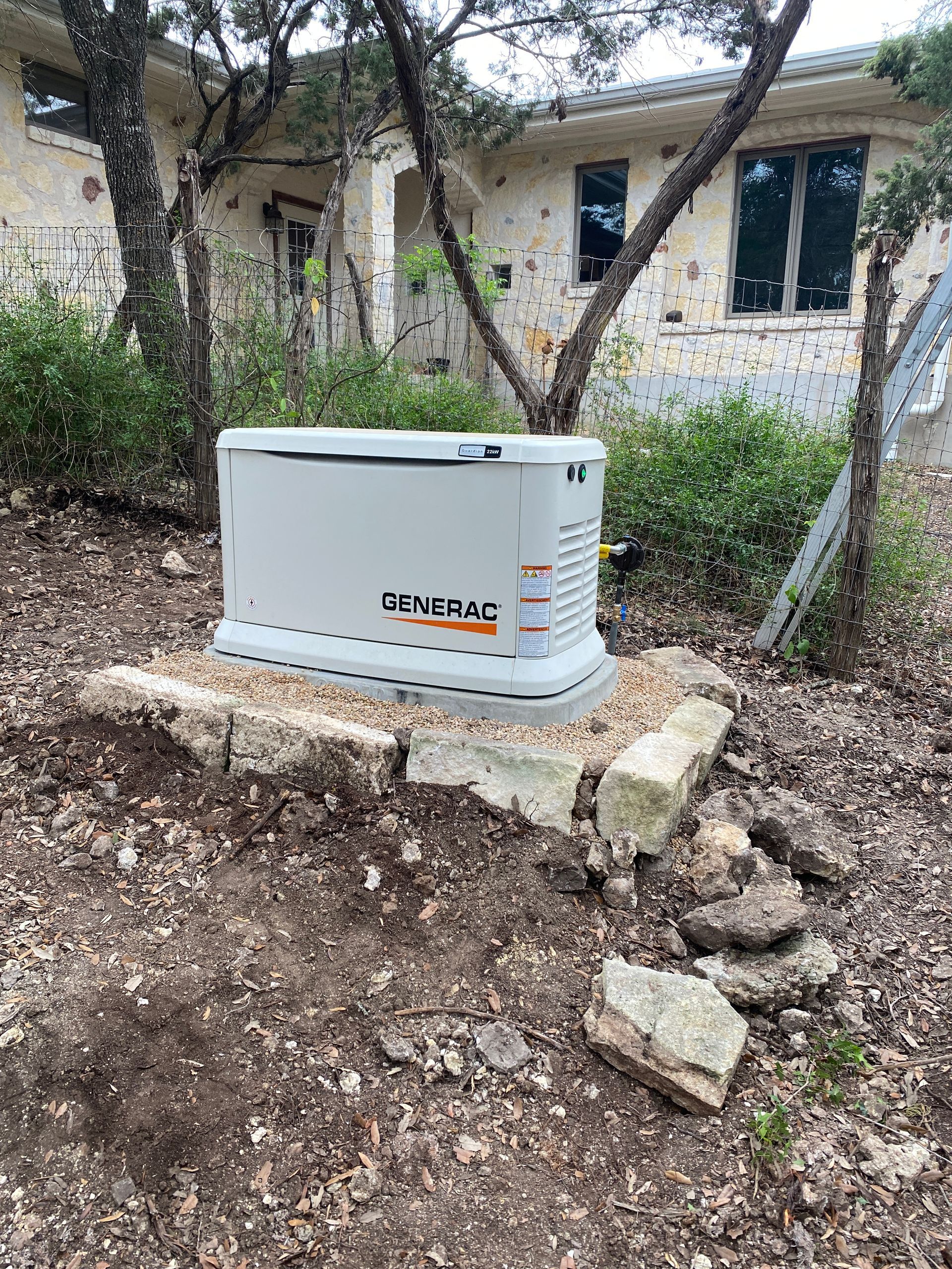 A generator is sitting in the dirt in front of a house.