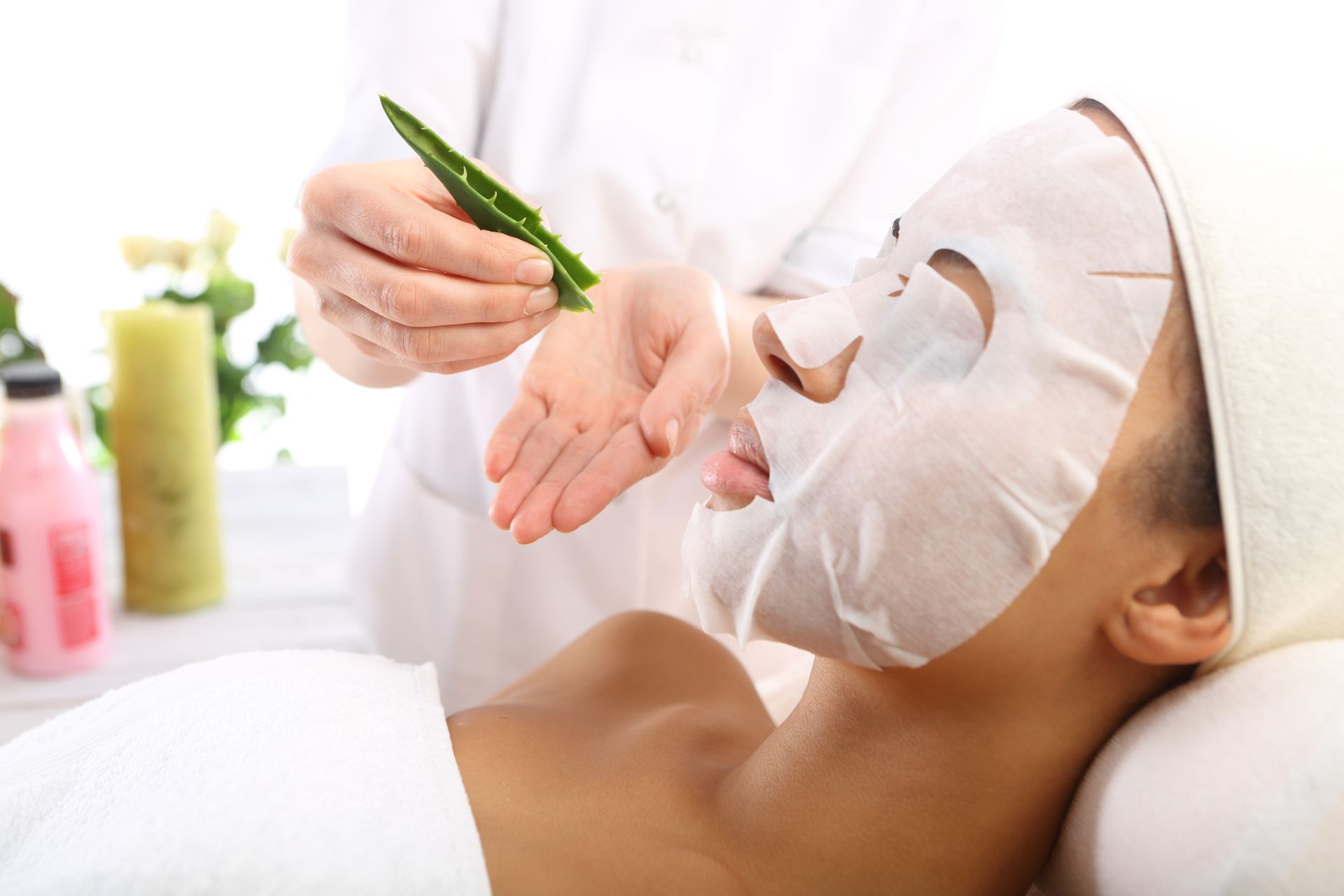 Person receiving a facial mask treatment at a spa, with a green brush applying product to the face