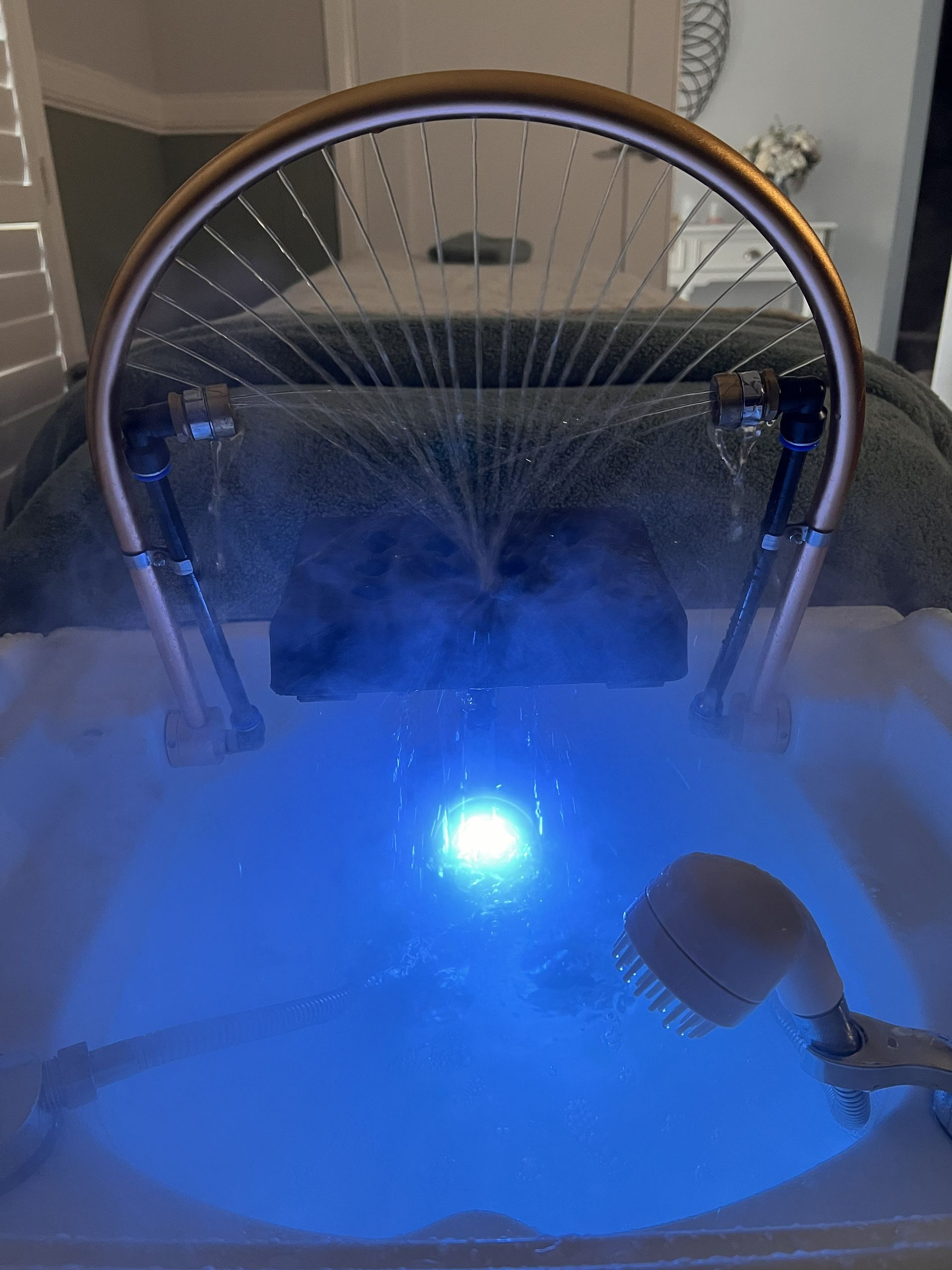 Round water fountain with blue light and mist spraying in a small indoor space