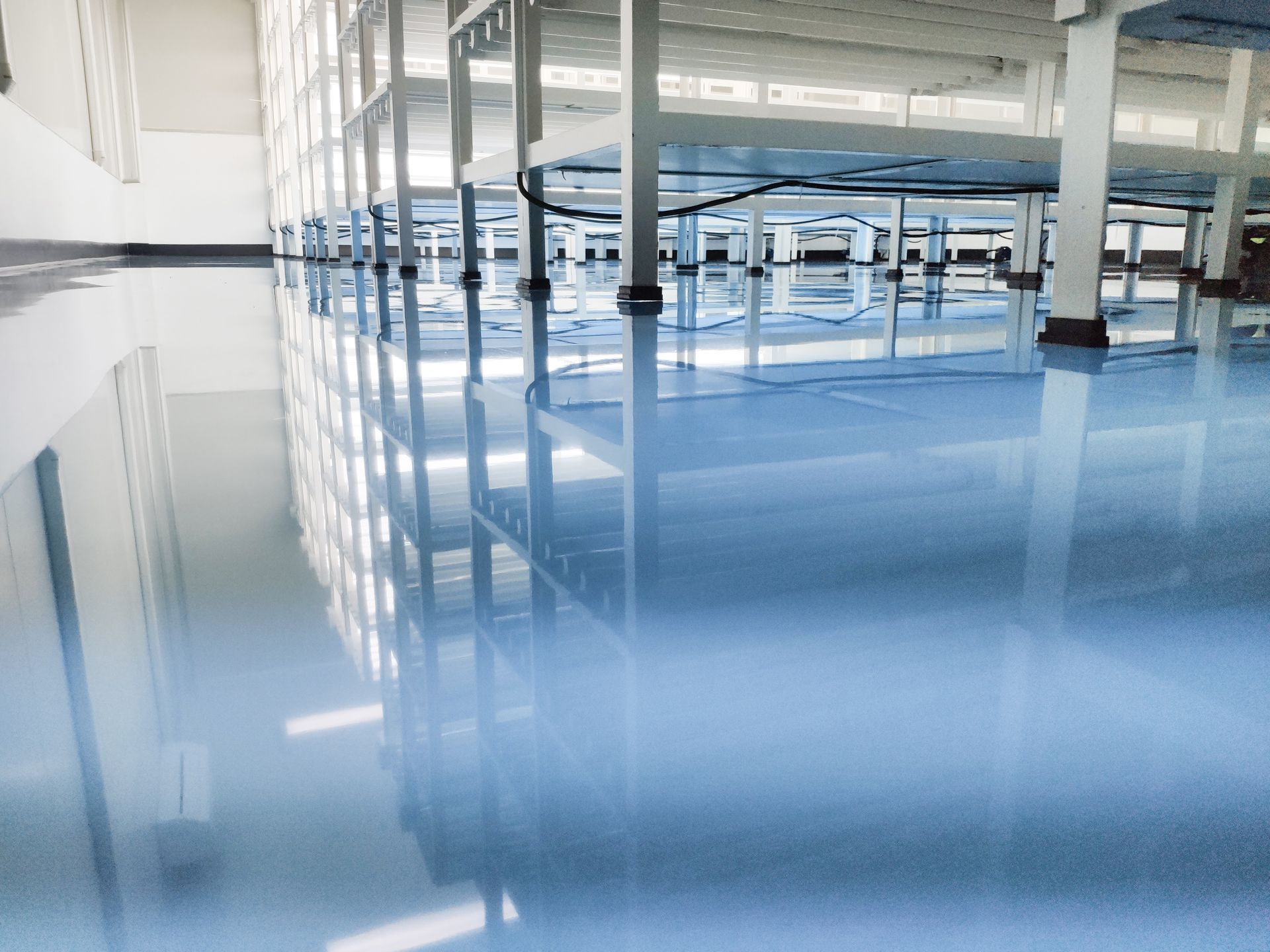 Empty modern hall with glossy blue floor and glass partitions reflecting light
