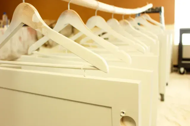 Row of white clothes hangers on a rack in a bright room