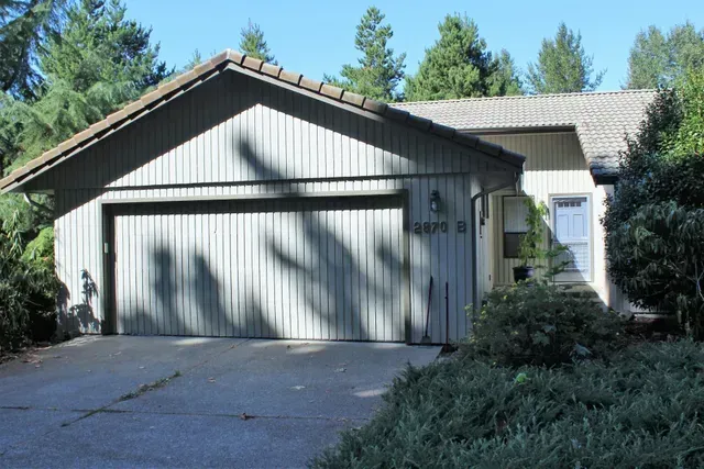 Suburban house with a two-car garage, driveway, and trees in front