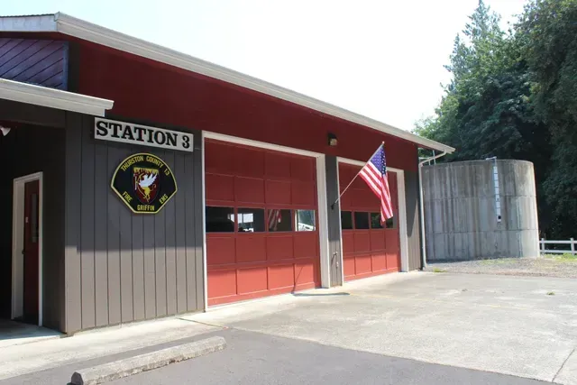 Fire station exterior with red garage doors, Station 3 sign, and an American flag on the building