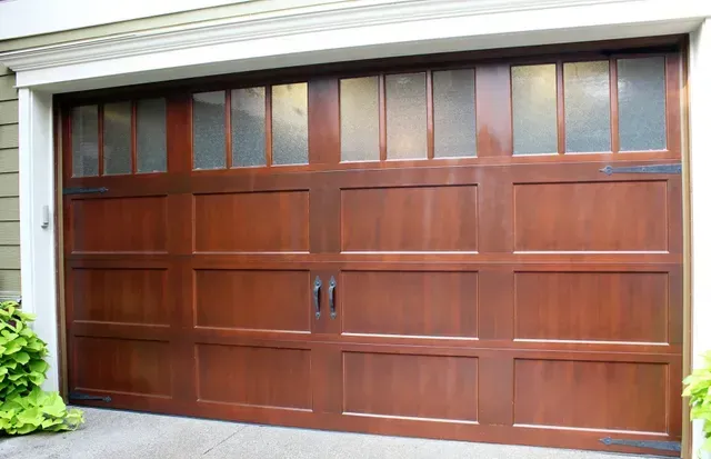Wooden two-car garage door with decorative window panels and black handles