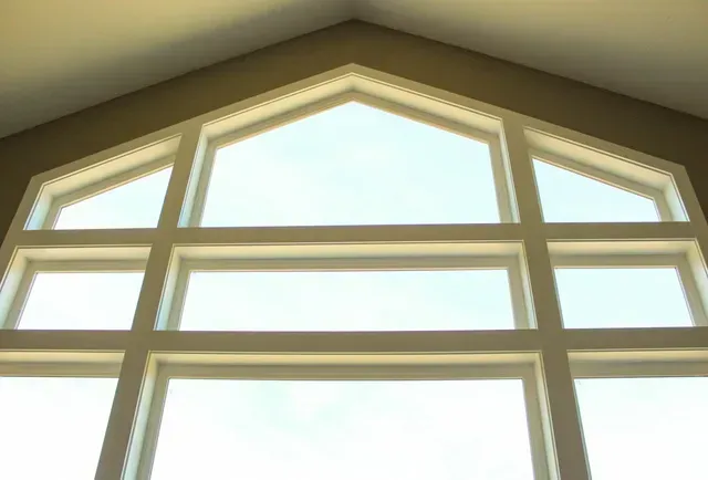 Tall arched window with white trim letting bright daylight into a room