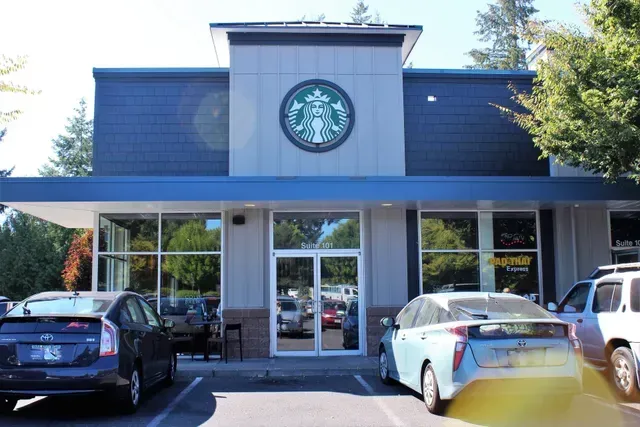Starbucks storefront with parked cars in front and the green logo above the entrance