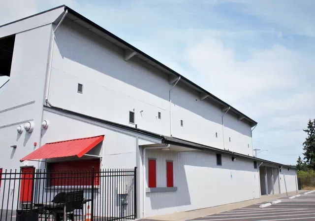 White building with a red awning and black gate on a street under a blue sky