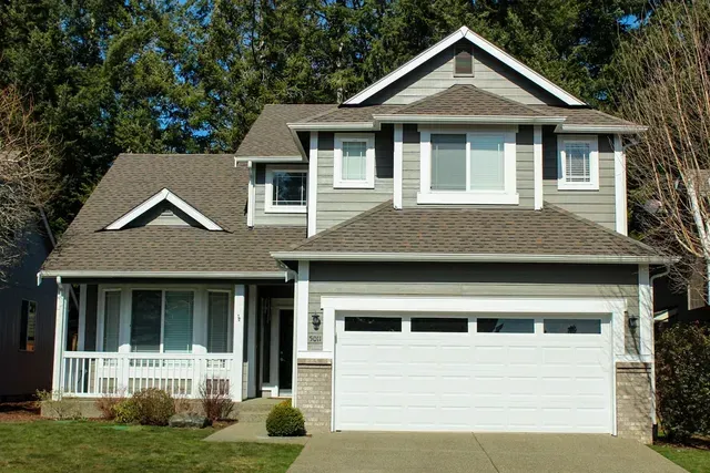 Two-story suburban house with white trim, gray siding, a front porch, and a two-car garage
