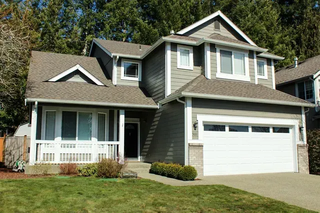 Suburban two-story house with gray siding, white trim, front porch, and attached garage