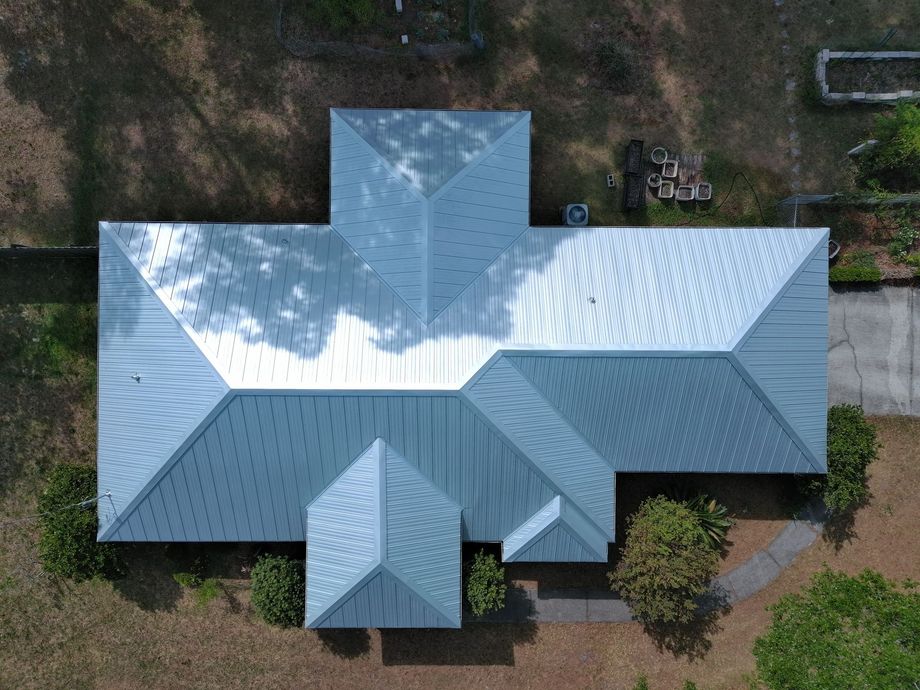 Aerial view of a single-story brick building with a gray roof, a small parking area, and landscaping in a grassy field.