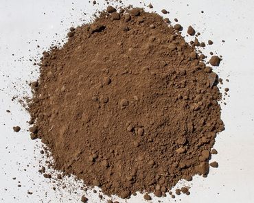 Pile of brown soil on a white surface.