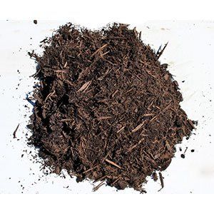 Pile of dark brown mulch on a white surface.