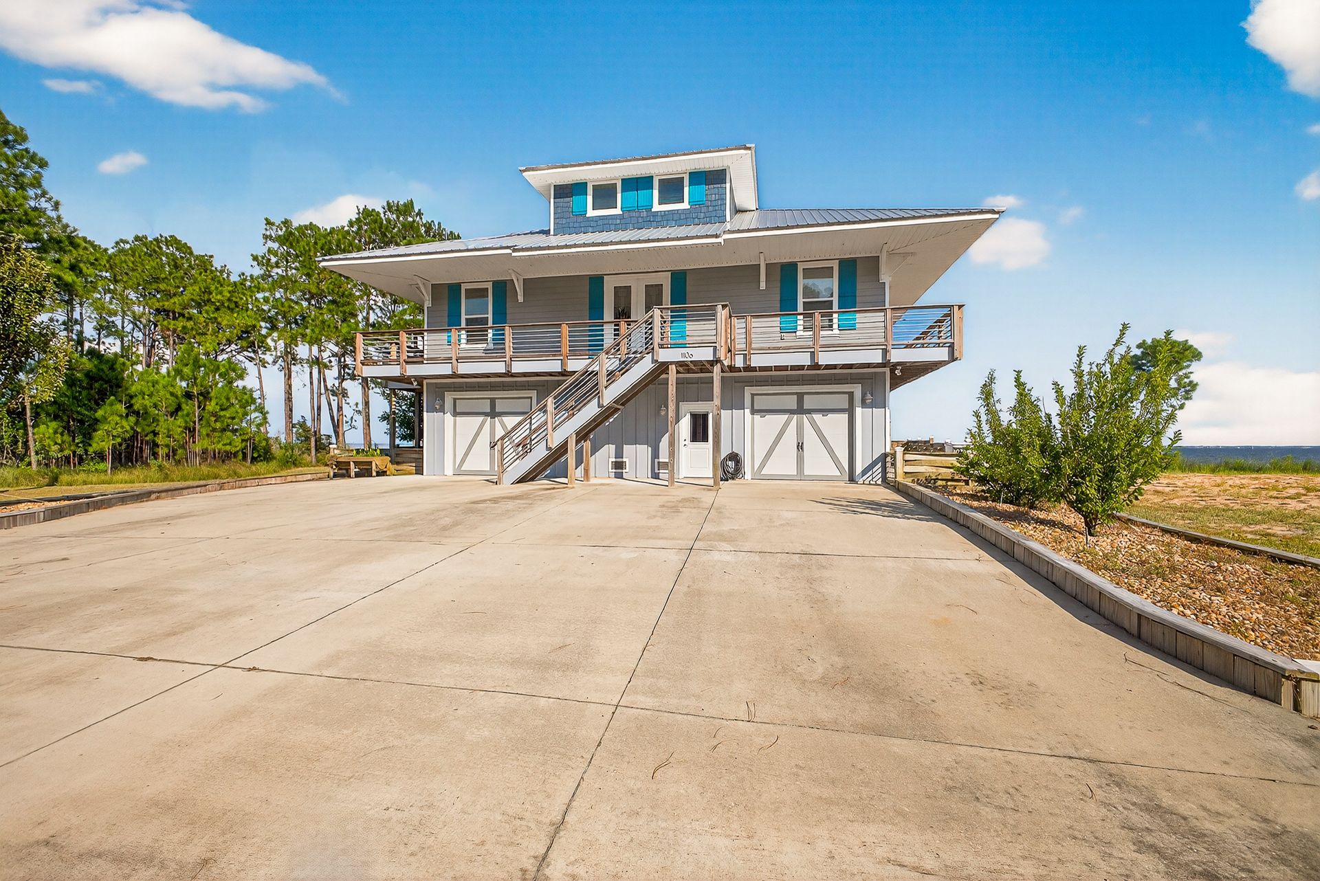 Two-story house with a wide concrete driveway, stairs, and a bright blue sky