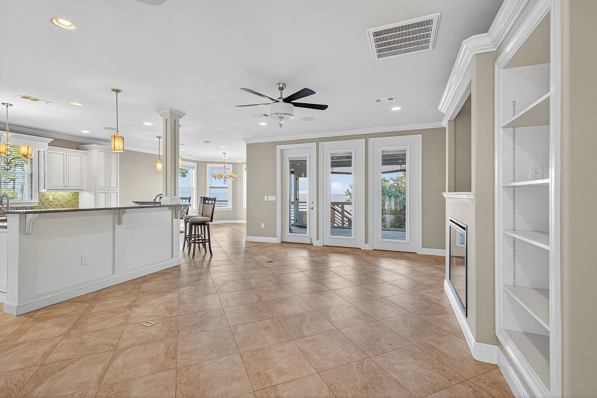 Bright open kitchen and living area with white cabinets, wood floors, and French doors.