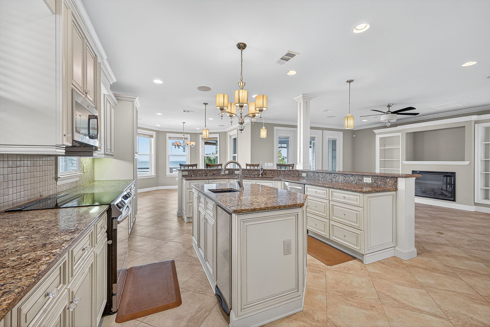 Bright, modern kitchen with white cabinets, granite islands, and chandelier lighting