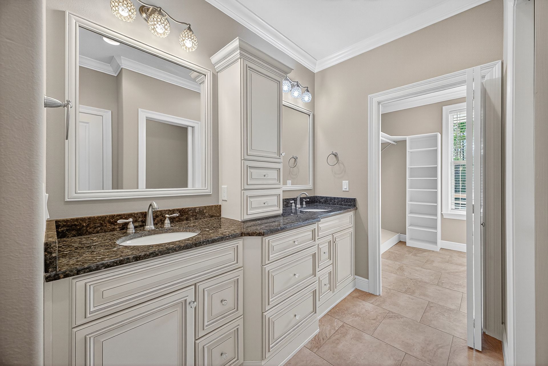 Elegant bathroom vanity with double sinks, large mirrors, and a doorway to an adjoining room