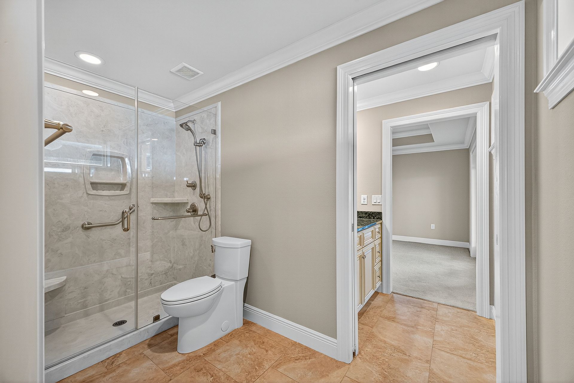 Modern bathroom with glass shower, toilet, and open doorway to adjacent room with beige walls and wood floor