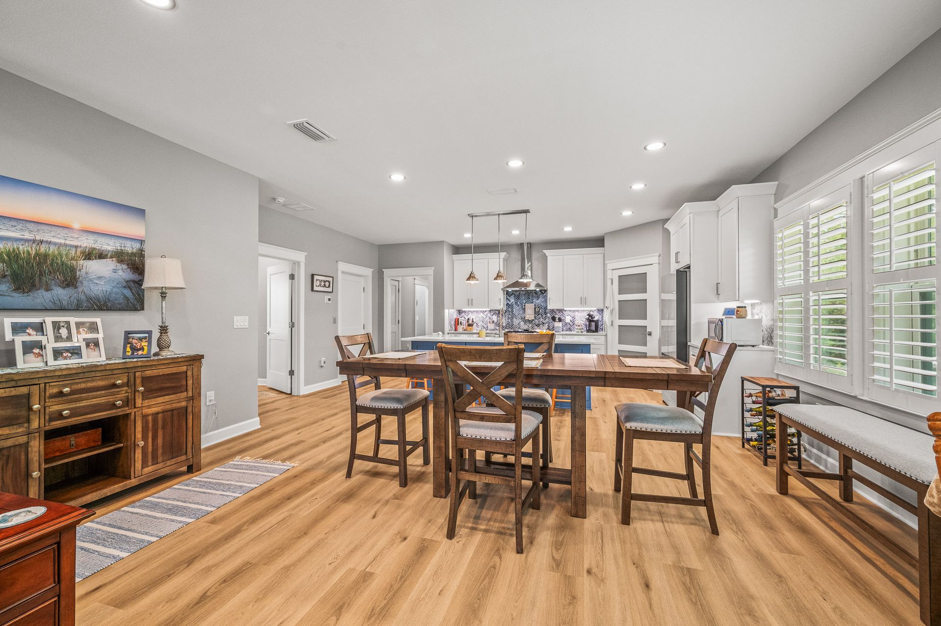 Bright open-concept kitchen and dining area with white cabinets, wood floors, and a large island