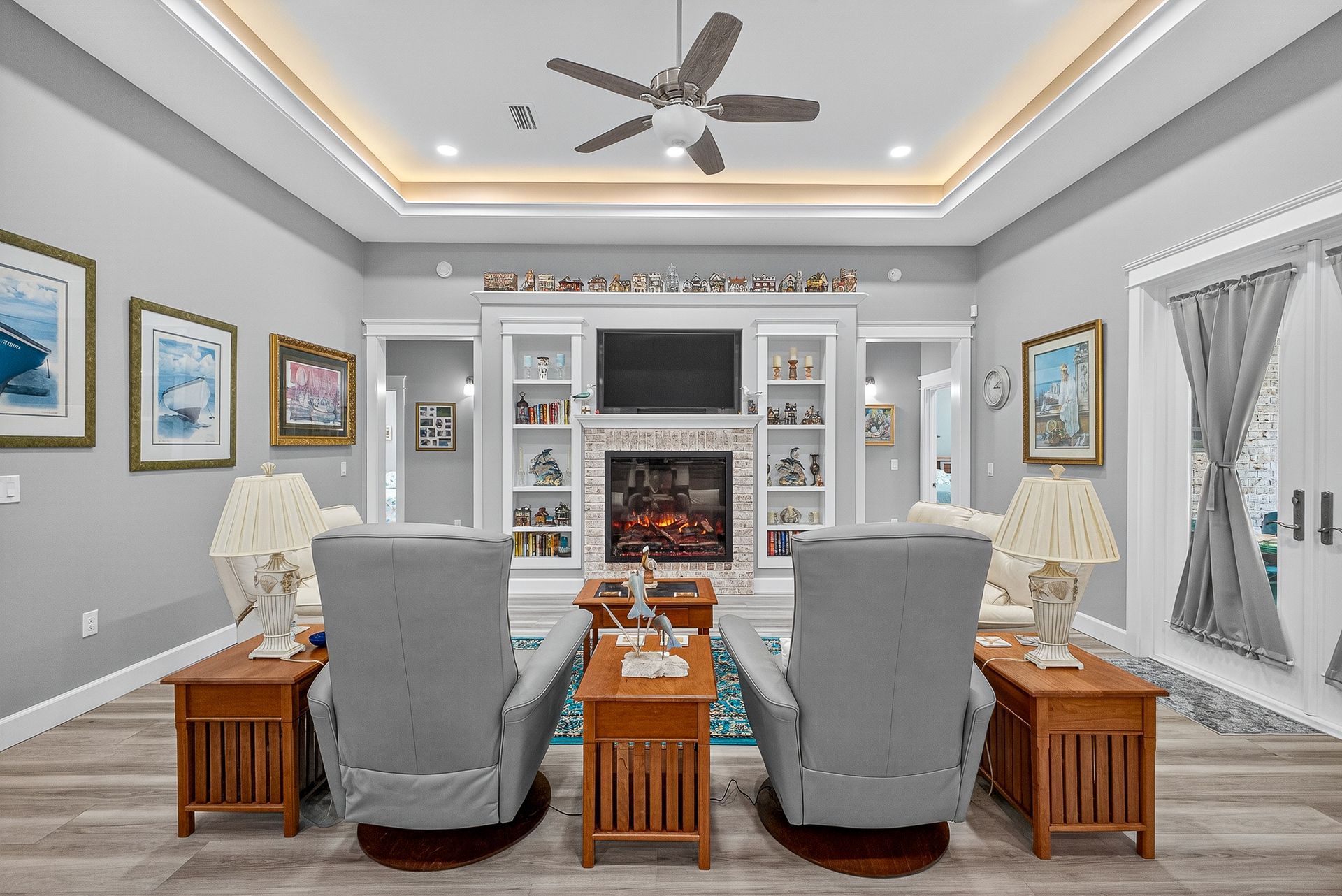 Modern living room with gray chairs, fireplace, built-in shelves, and ceiling fan
