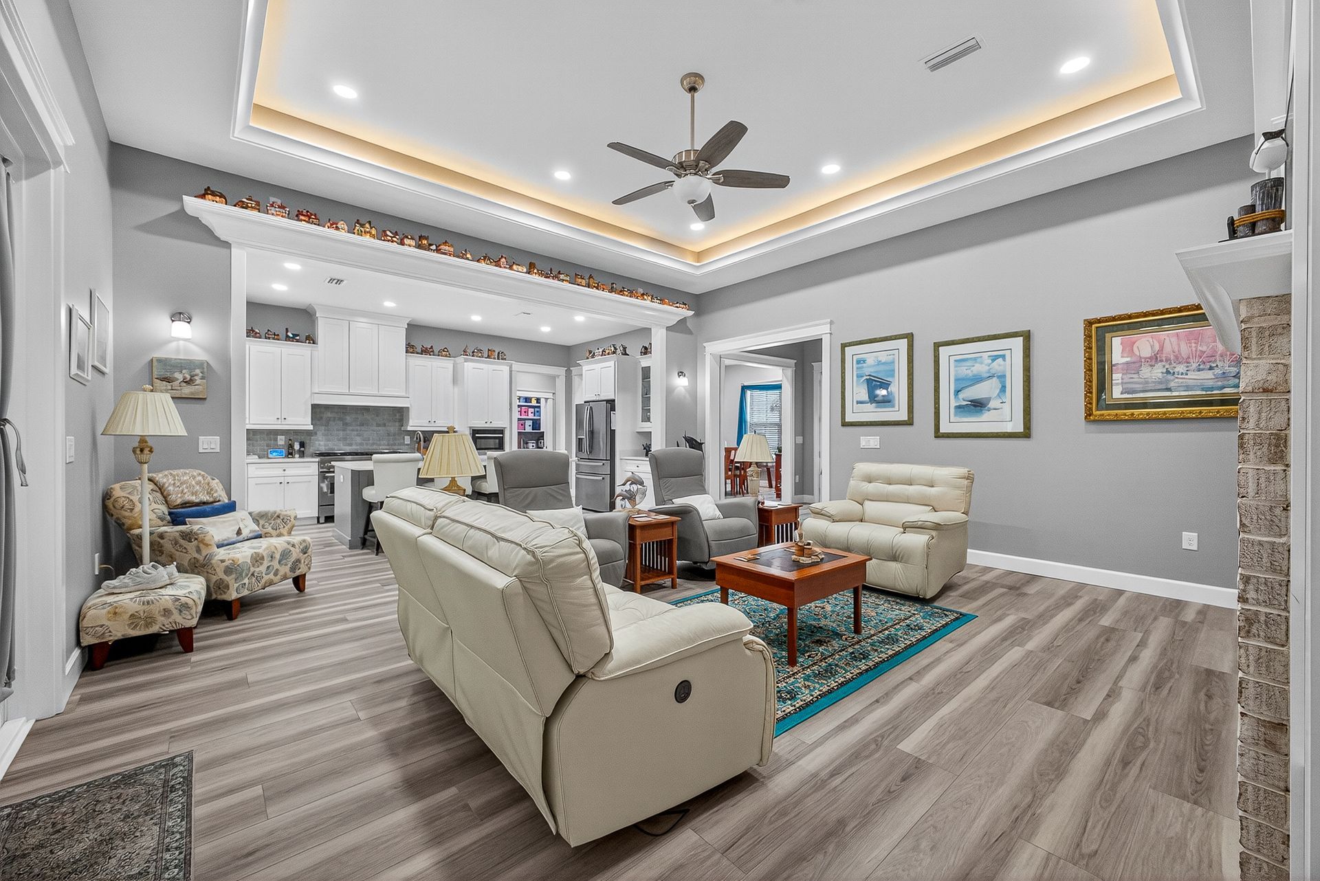 Bright modern living room with beige seating, gray walls, wood floors, and recessed ceiling lighting