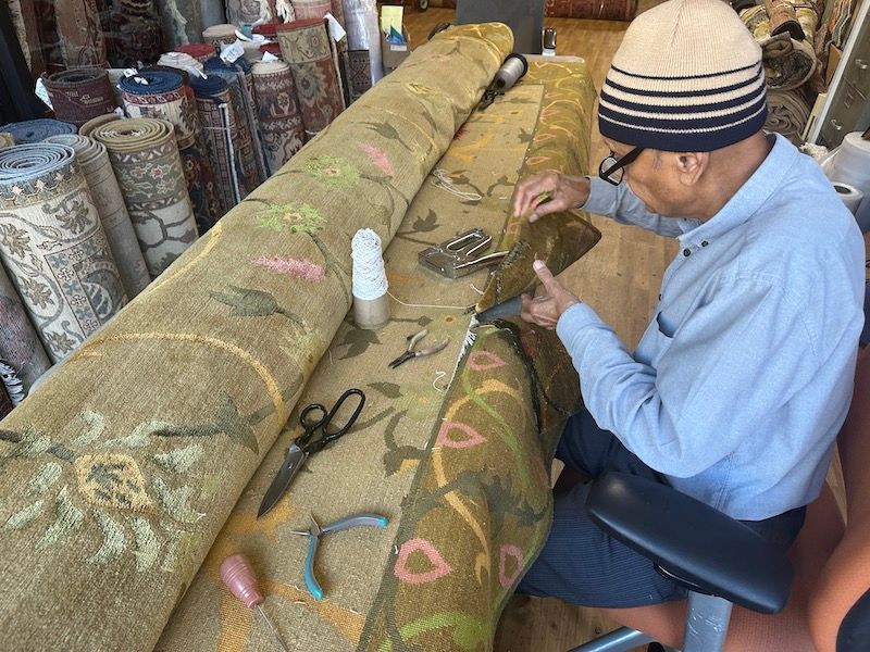 Skilled technician hand-repairing a vintage rug at Rug Master in Burlingame, CA.
